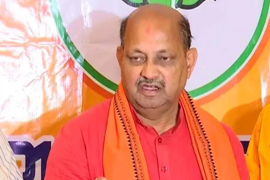 Manmohan Samal speaking at a press briefing, wearing an orange kurta and shawl.