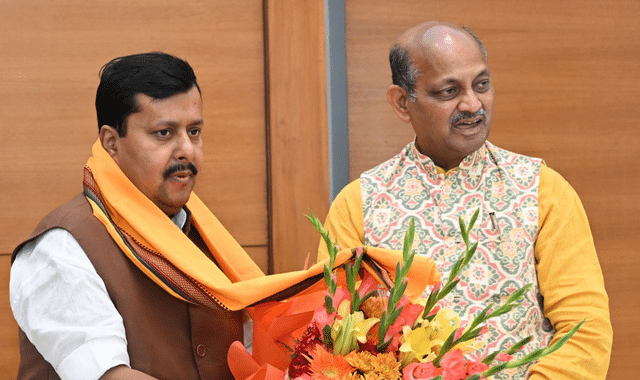 Manmohan Samal receiving a bouquet of flowers from a colleague at an indoor party function.