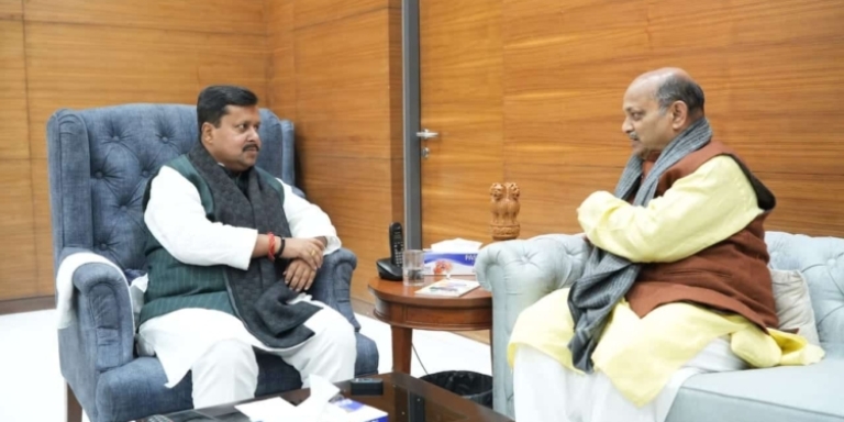 Manmohan Samal seated in conversation with a colleague in a wood-panelled office.