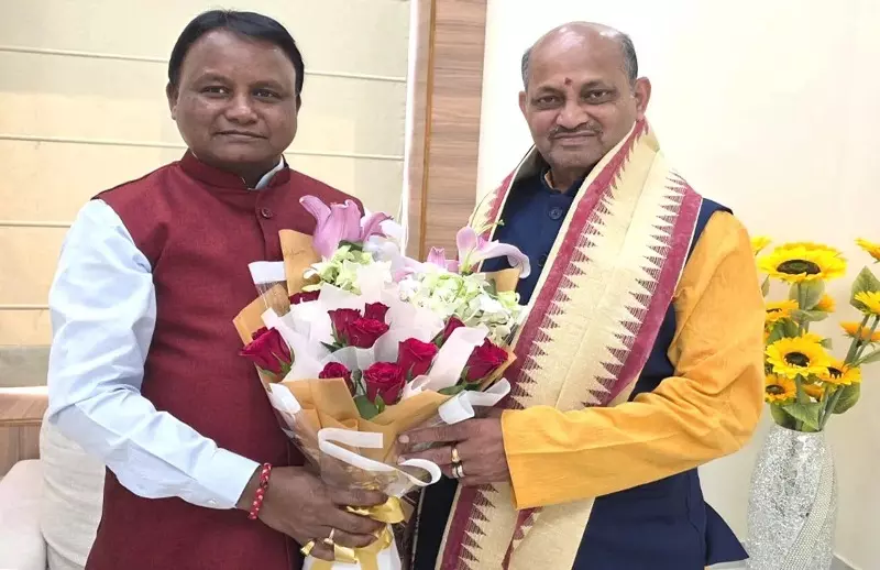 Chief Minister Mohan Charan Majhi presenting a bouquet of flowers to Manmohan Samal indoors.