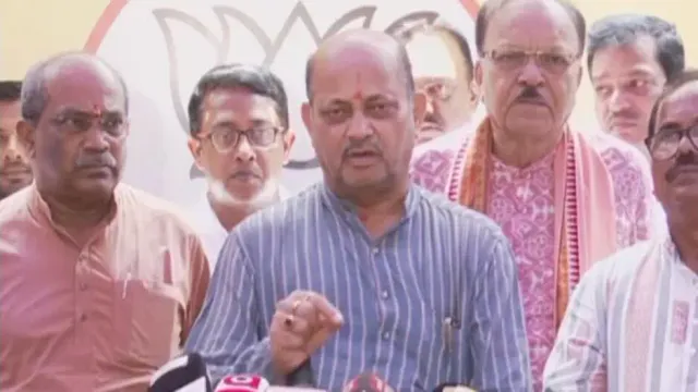 Manmohan Samal speaking at a briefing with several party colleagues standing on either side of him.