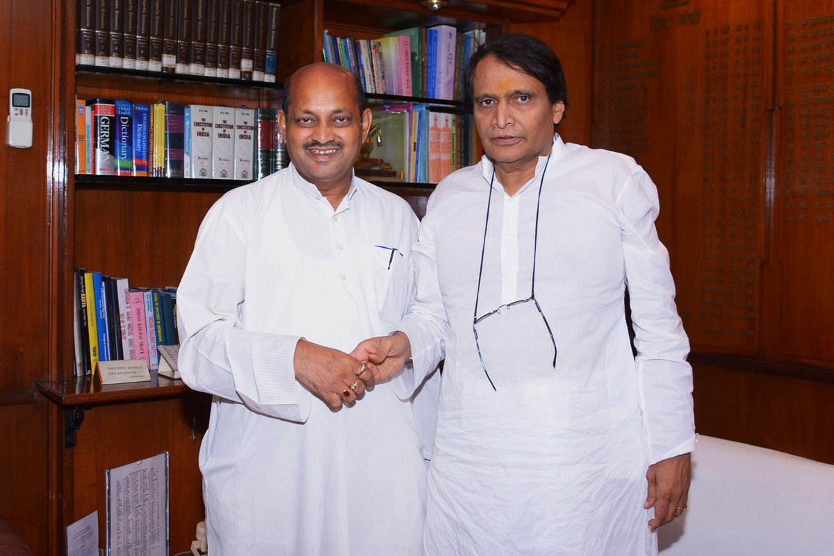 Manmohan Samal standing beside a senior colleague in a wood-panelled office lined with bookshelves.