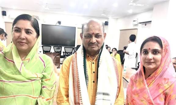 Manmohan Samal standing between two women colleagues at an indoor party gathering.