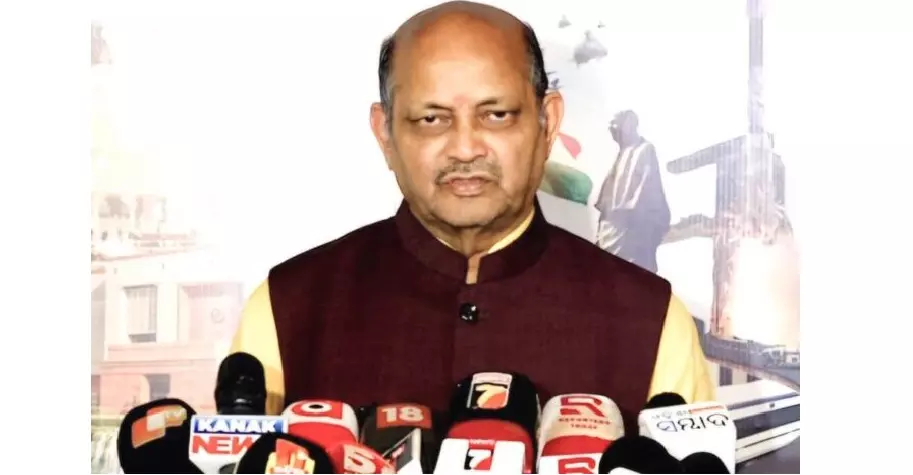 Manmohan Samal making a statement to reporters before a backdrop showing a temple illustration.